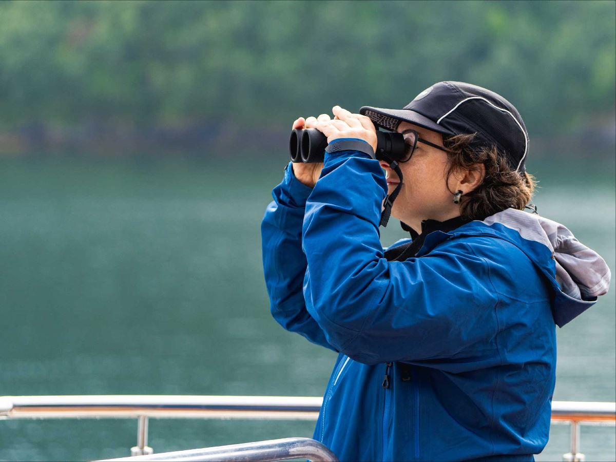 A guest watches into the distance with binoculars