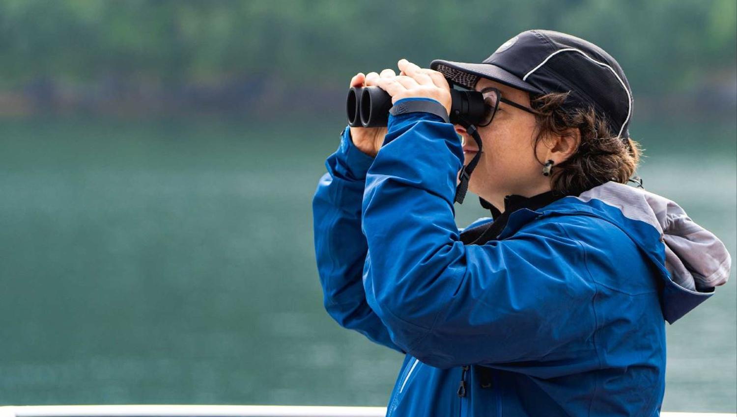 A guest watches into the distance with binoculars