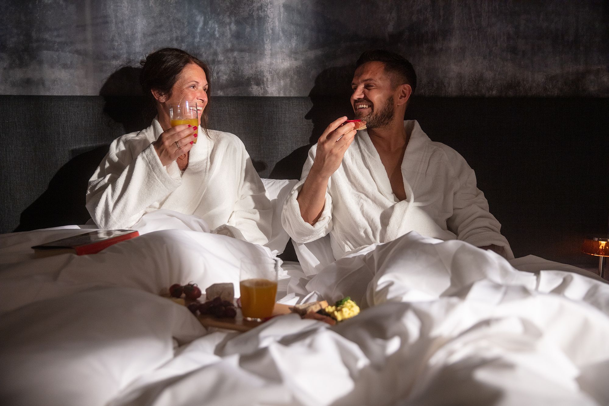 Couple enjoying breakfast in bed at Hardanger House, perfect for romantic stays.