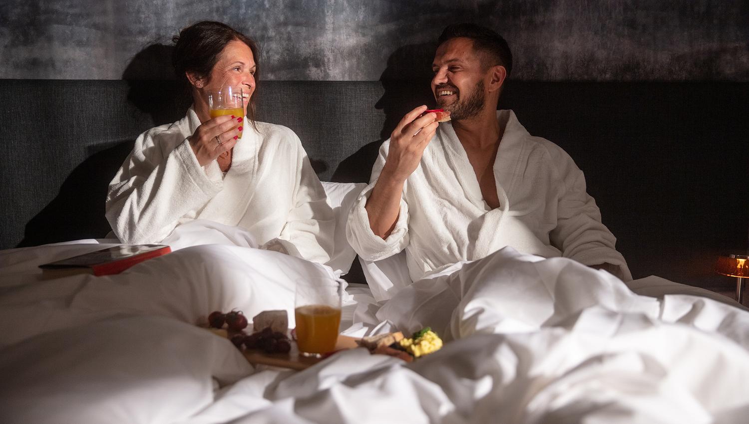 Couple enjoying breakfast in bed at Hardanger House, perfect for romantic stays.