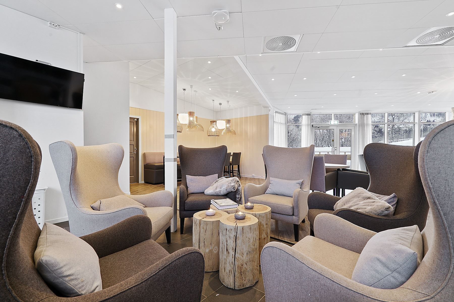 Lounge area with six armchairs arranged in a circle and natural light from large windows