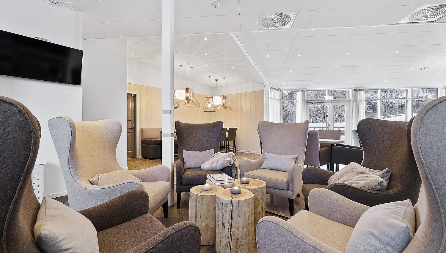 Lounge area with six armchairs arranged in a circle and natural light from large windows