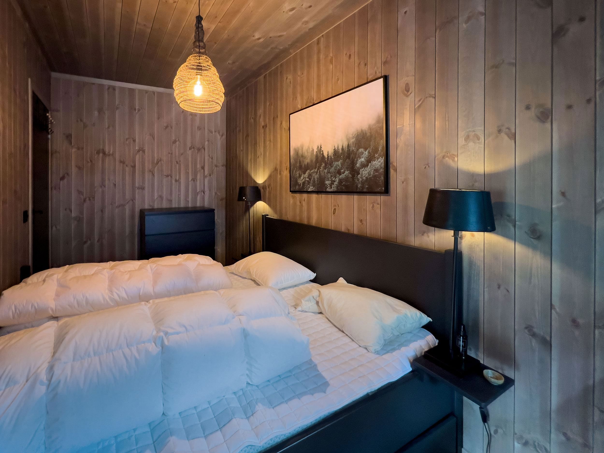 A bed with white sheets and a lamp in a room.