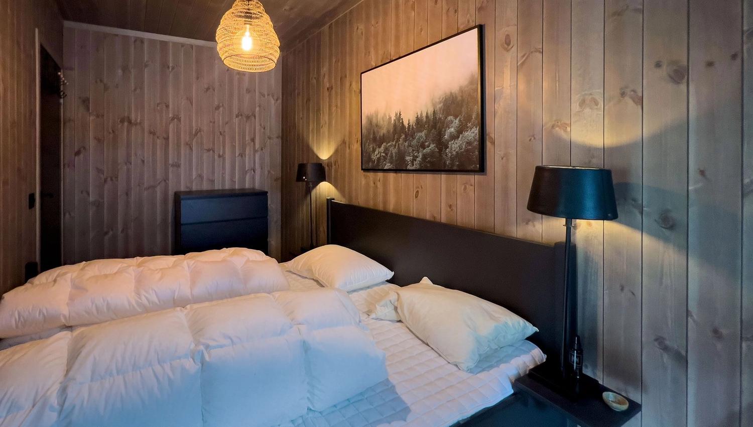 A bed with white sheets and a lamp in a room.