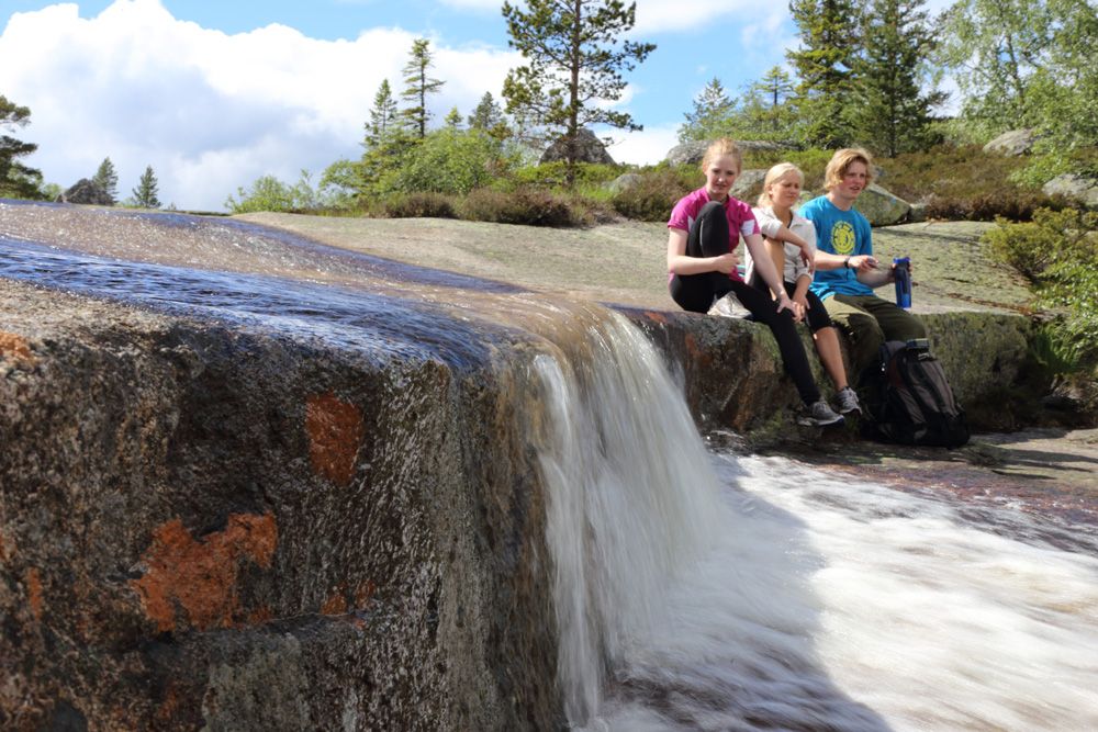 gruppe ungdom sitter ved en liten foss