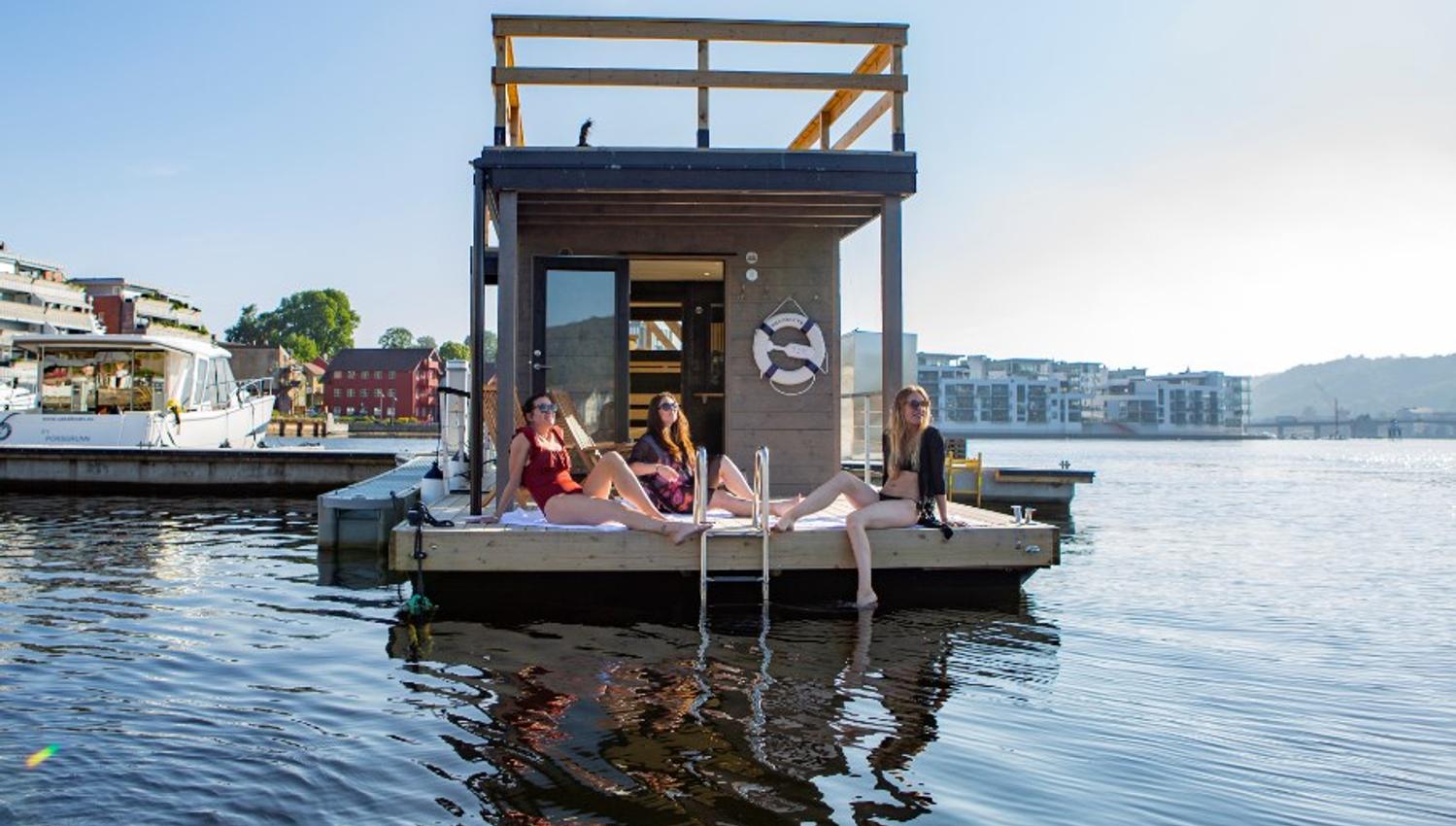 Saunaboat Melvin I Porsgrunn. Bilde av saunabåten ved bryggekanten i Porsgrunn med 3 jenter som ligger og soler seg foran på dekket