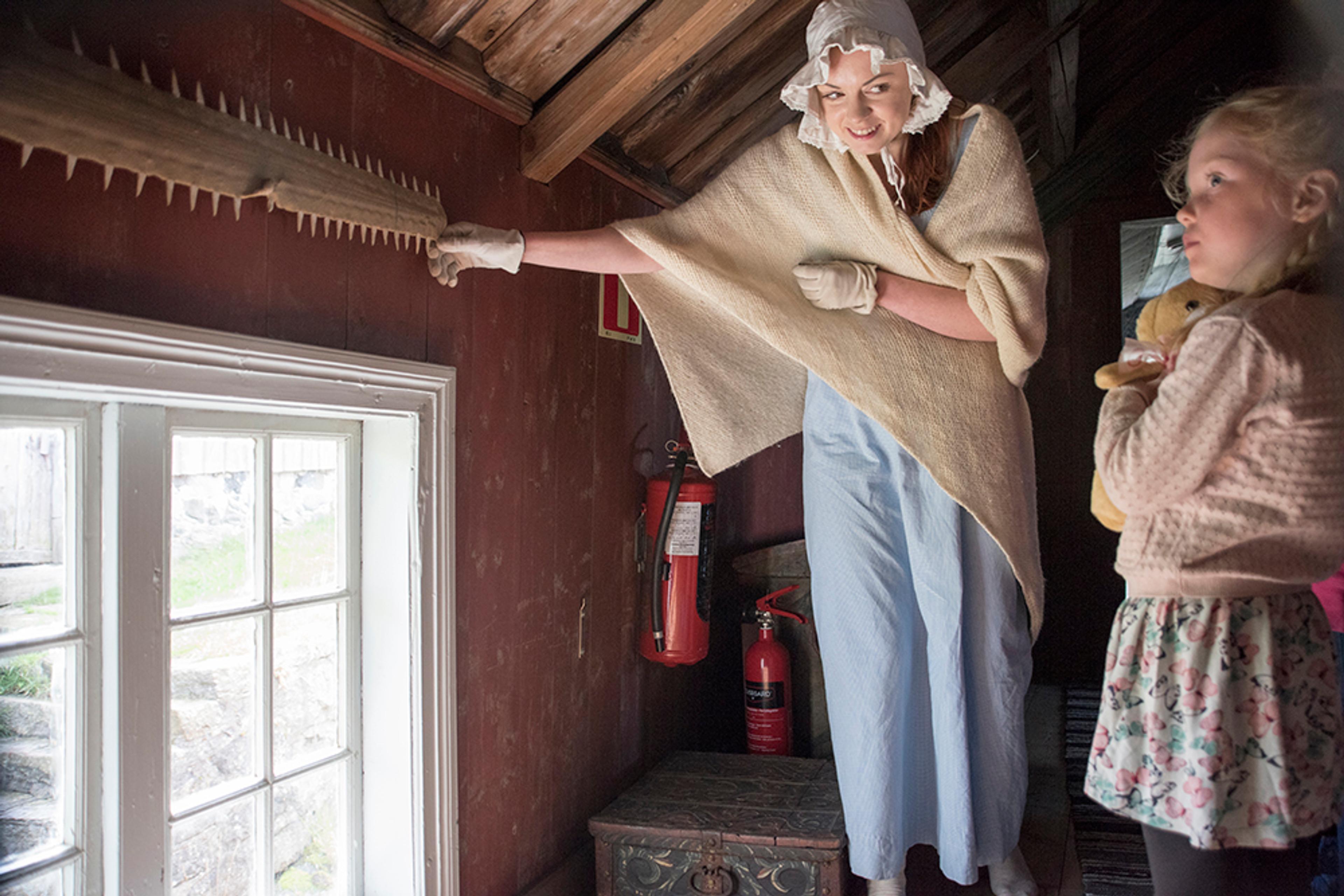Guiden peker og forteller på Merdøgaard museum