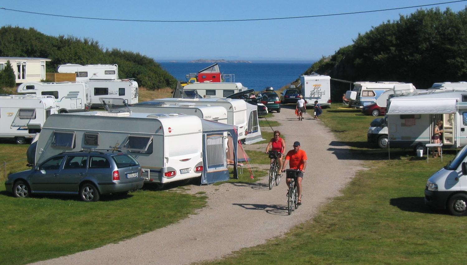 Lindesnes Camping og Hytteutleie, en sti lang mellom campingvognene. To syklister med knallrøde t-skjorter sykler på stien.