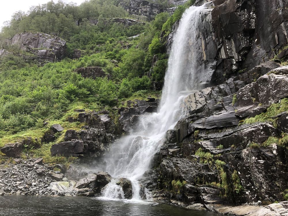 Majestetisk fossefall omgitt av frodig natur i Hardangerfjorden, ein attraksjon på Norheimsund RIB Seafari.