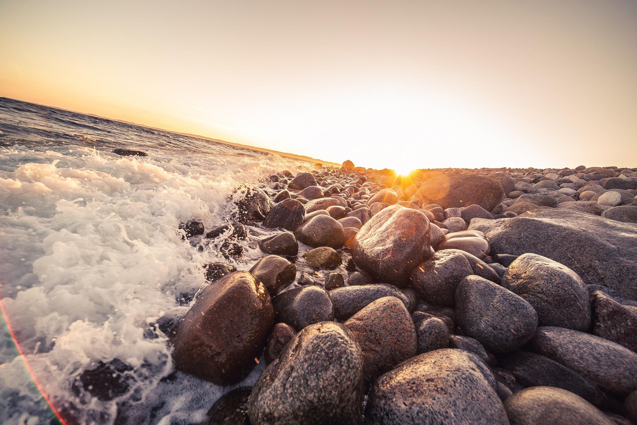 Rolling stones on Mølen in the water with sunset
