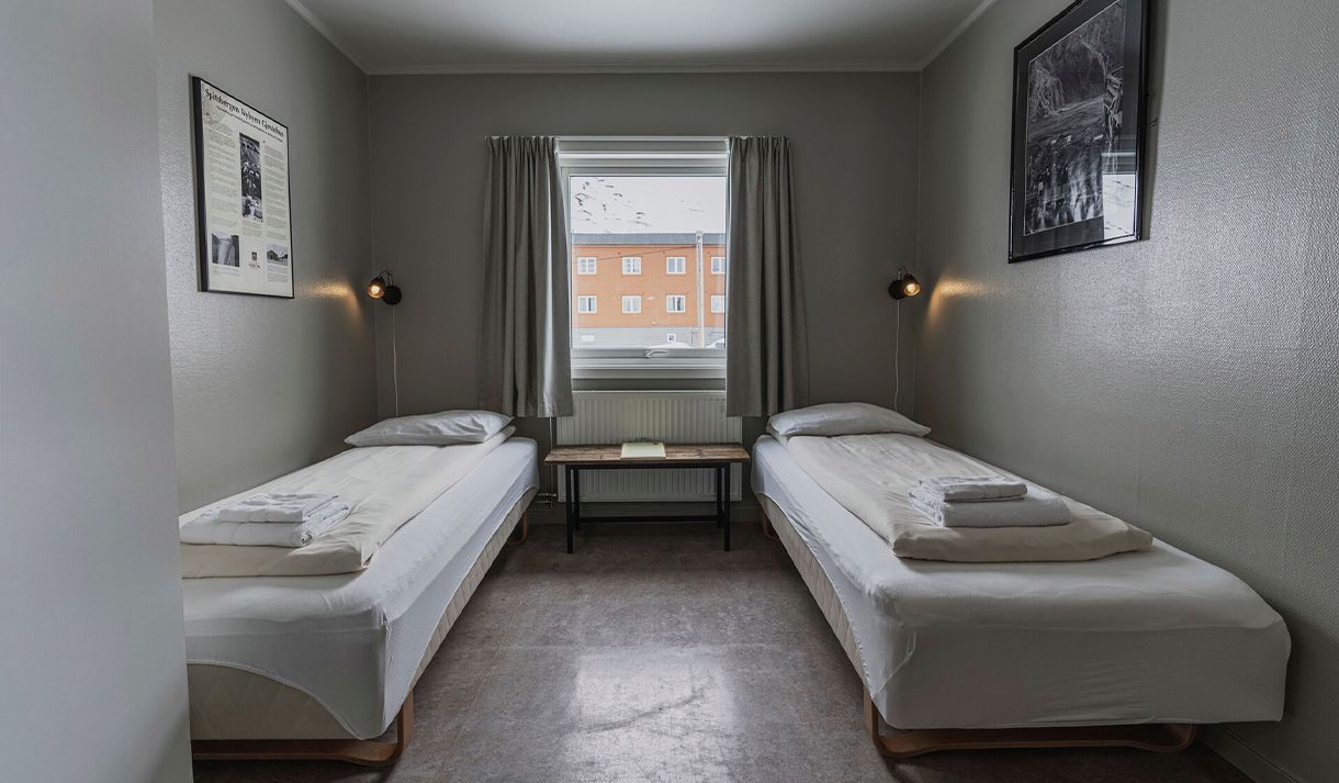 A bedroom at Coal Miners' Cabins with two single beds and a window in the background