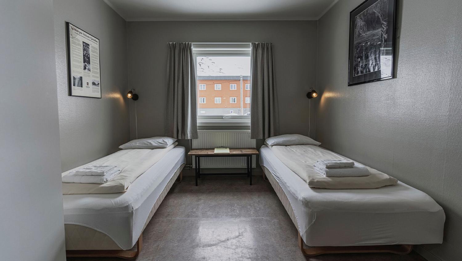 A bedroom at Coal Miners' Cabins with two single beds and a window in the background