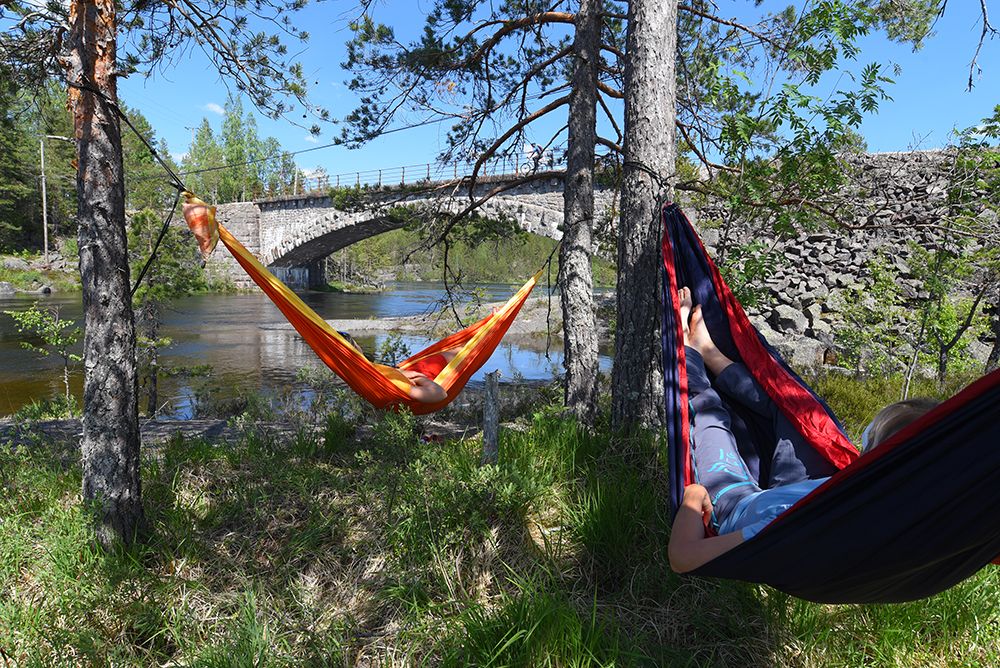 2 syklister slapper av i hver sin hengekøye langs sykkelveien "gamle Treungenbanen"
