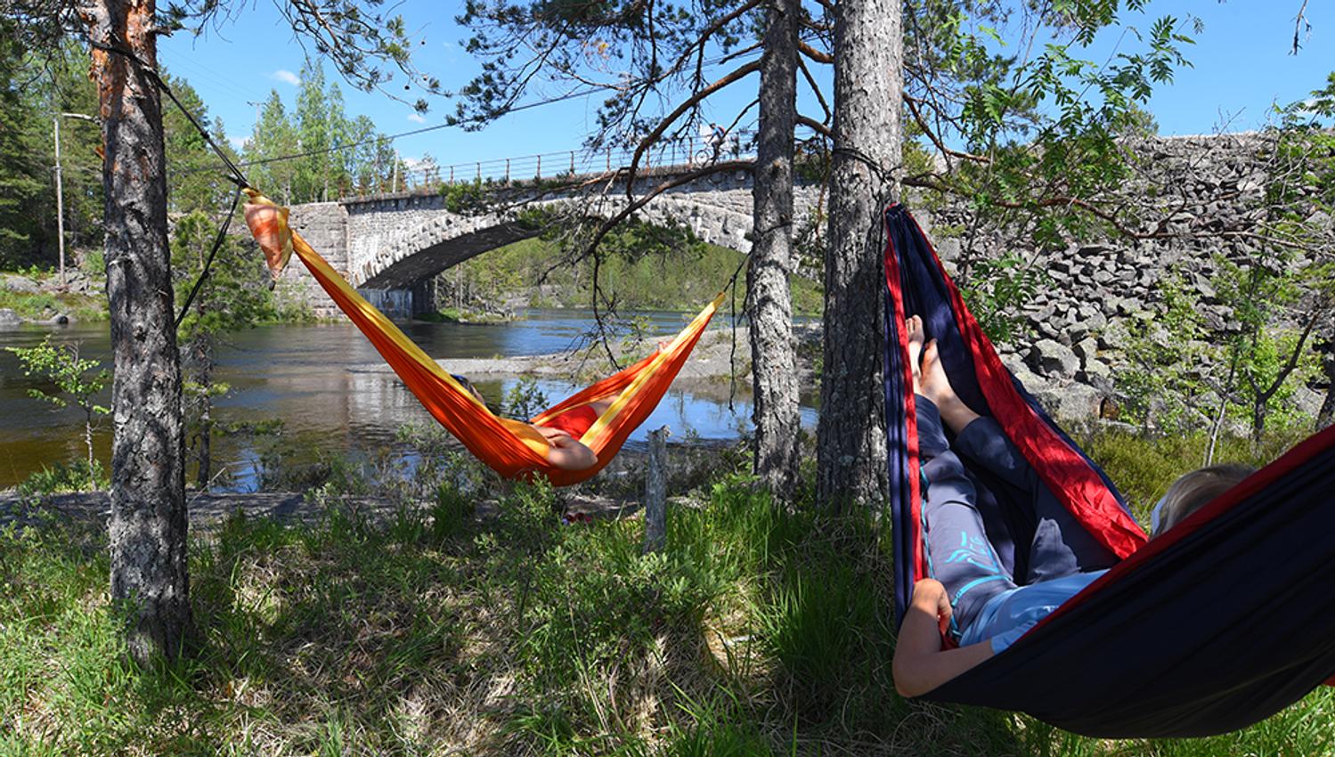 2 syklister slapper av i hver sin hengekøye langs sykkelveien "gamle Treungenbanen"