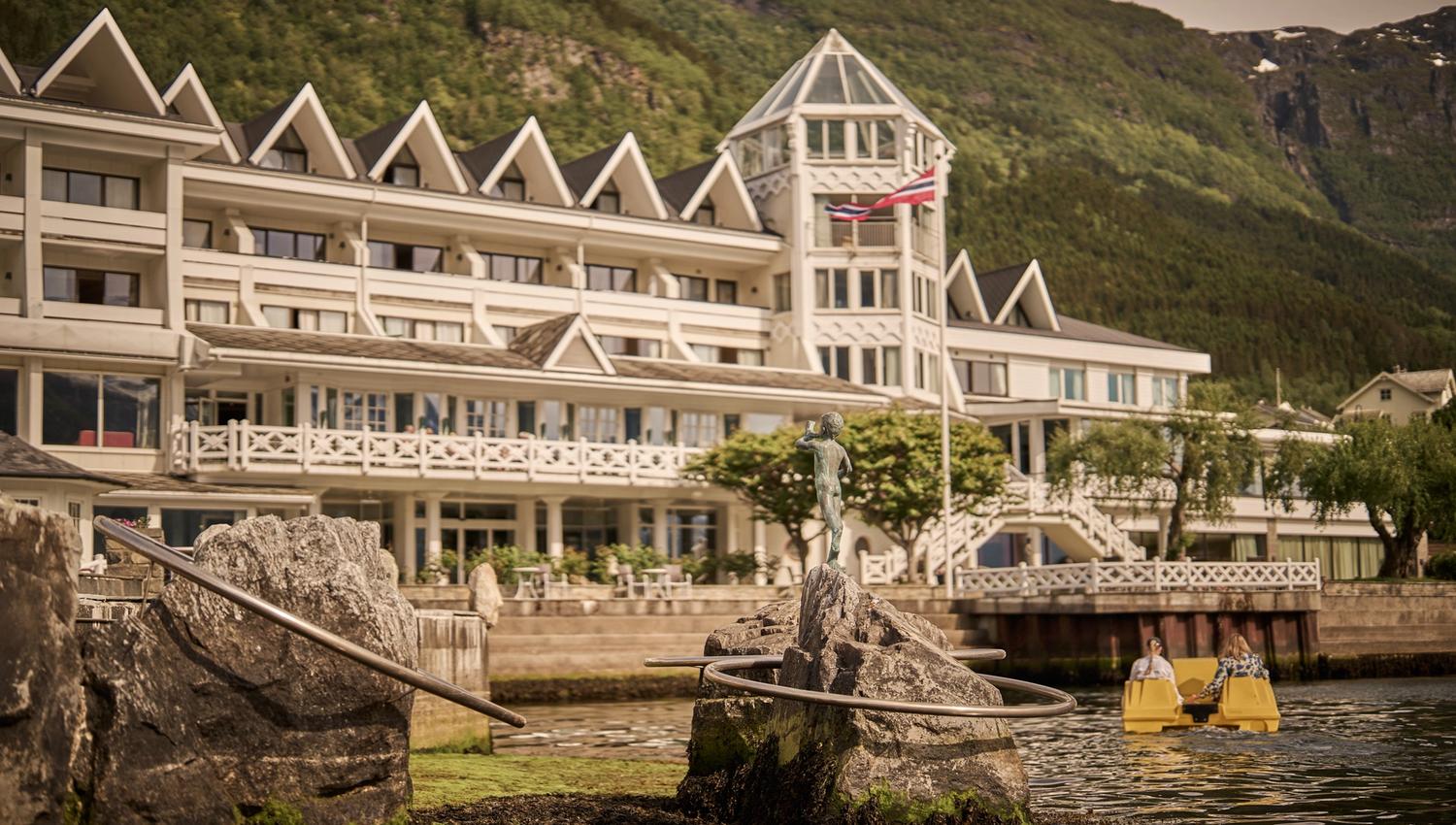 Gjestene kosar seg i pedalbåt med Hotel Ullensvang og fjella i bakgrunnen.