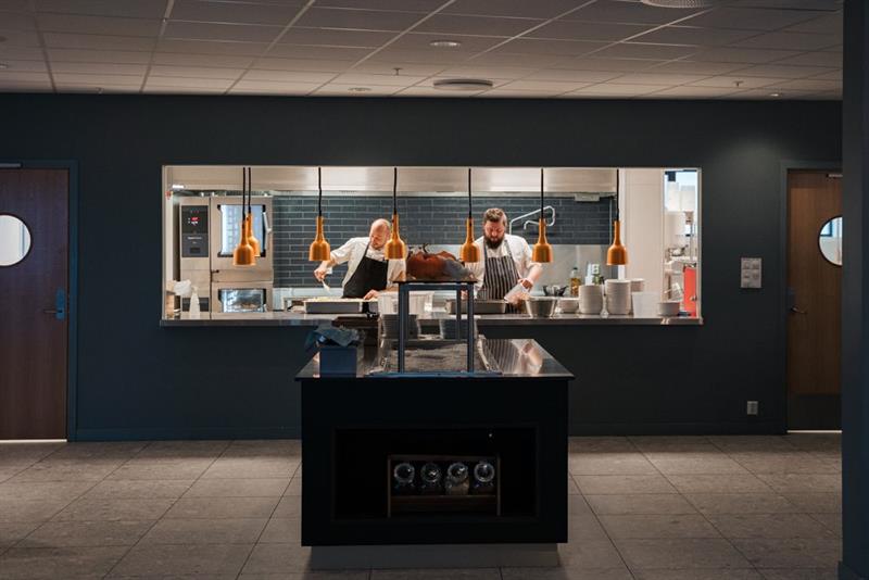 To kokker står og lager mat på kjøkkenet i en restaurant.