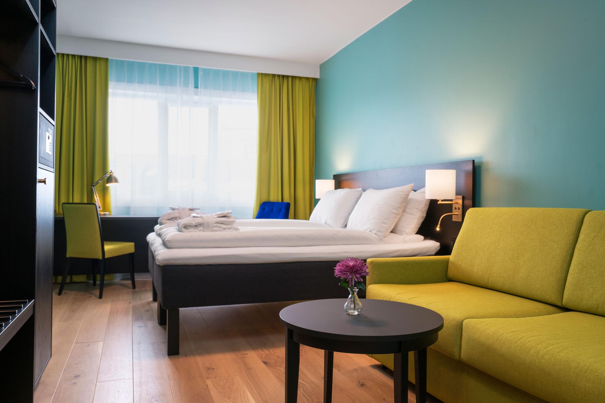 Fargerikt dobbeltrom med seng, sofa, skap og skrivebord