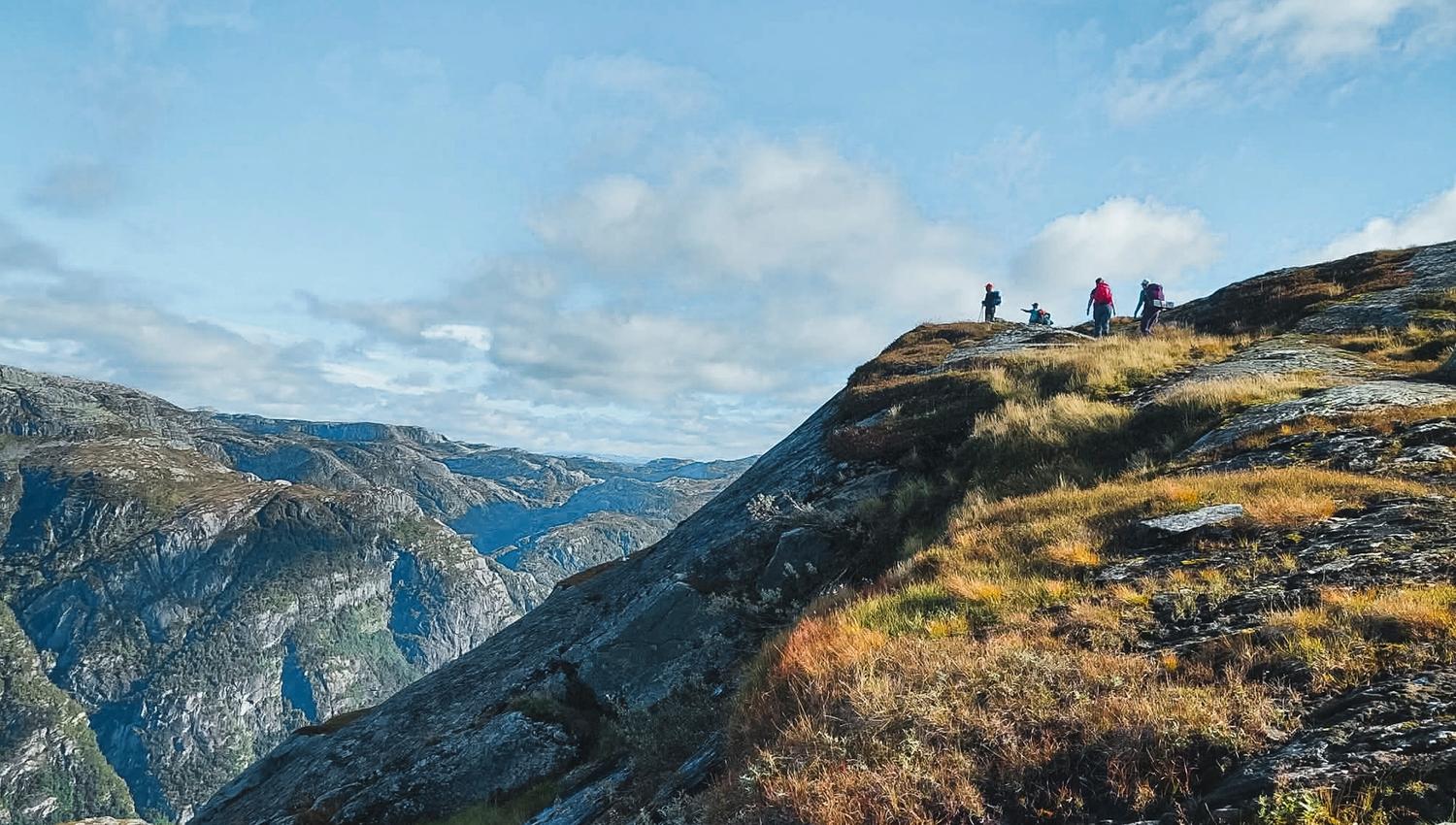 Hikers on a mountain ridge overlooking dramatic landscapes in Hardanger, Norway, ideal for hiking and outdoor adventures