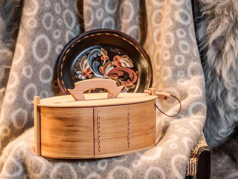 Detaljbilde av treboks og en håndmalt tallerken i tre.