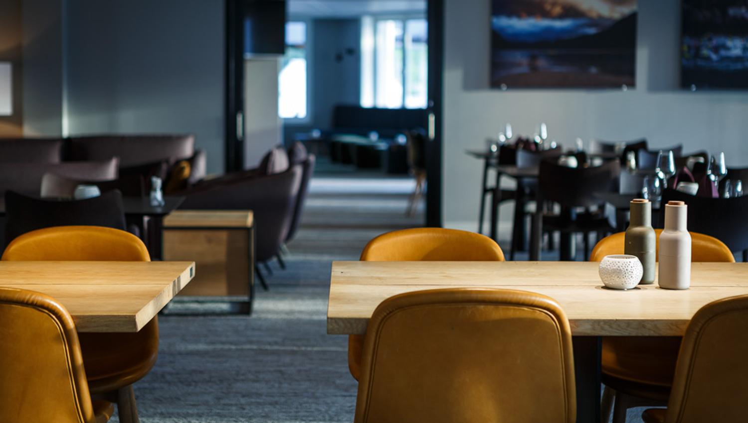 Spisesalen på restauranten med bord, stoler og utsikt mot barområdet i bakgrunnen.
