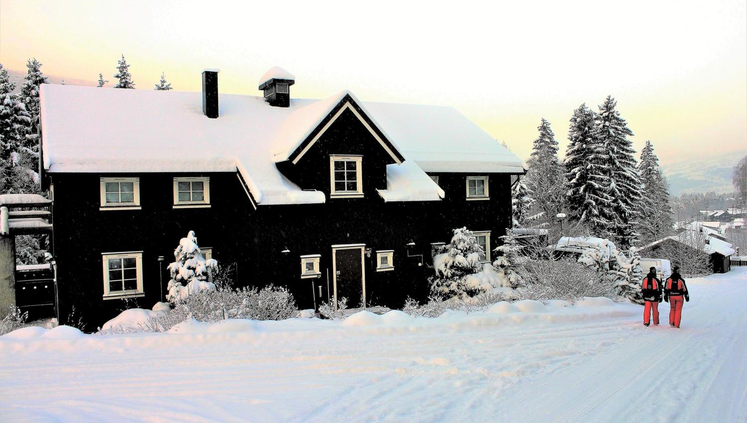 The barn is a large cabin with snow on the ground.