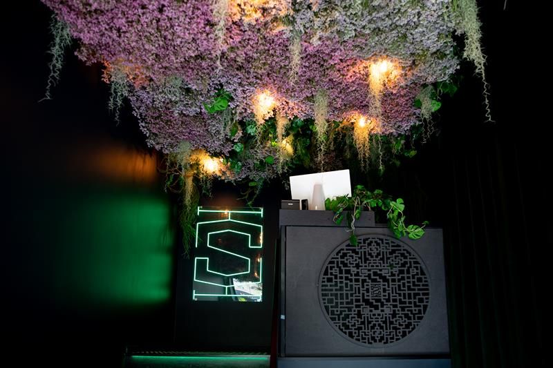 Inngangsparti med vegetasjon i taket, disk og grønt neonskilt