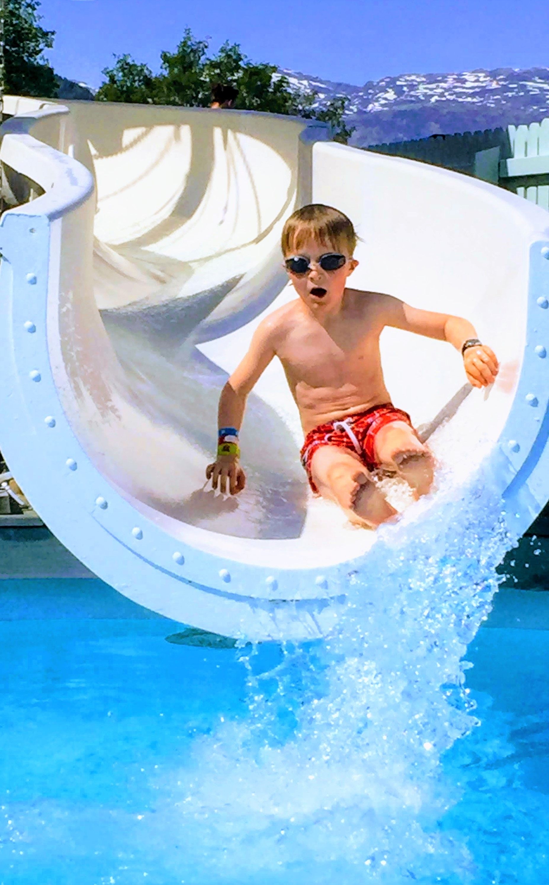 Child sliding down a water slide in the pool area at Mikkelparken