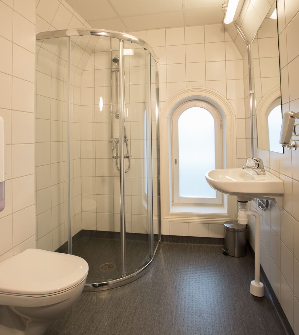 Bad med dusj. Hvite fliser, mørkt gulv. Saga Hotel & Poshtel Oslo Central. Foto