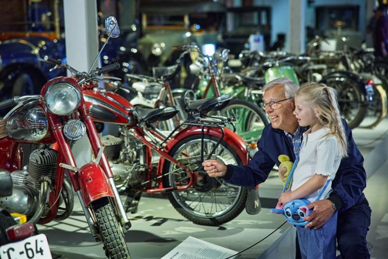 En eldre mann og en liten jente som ser på motorsykler