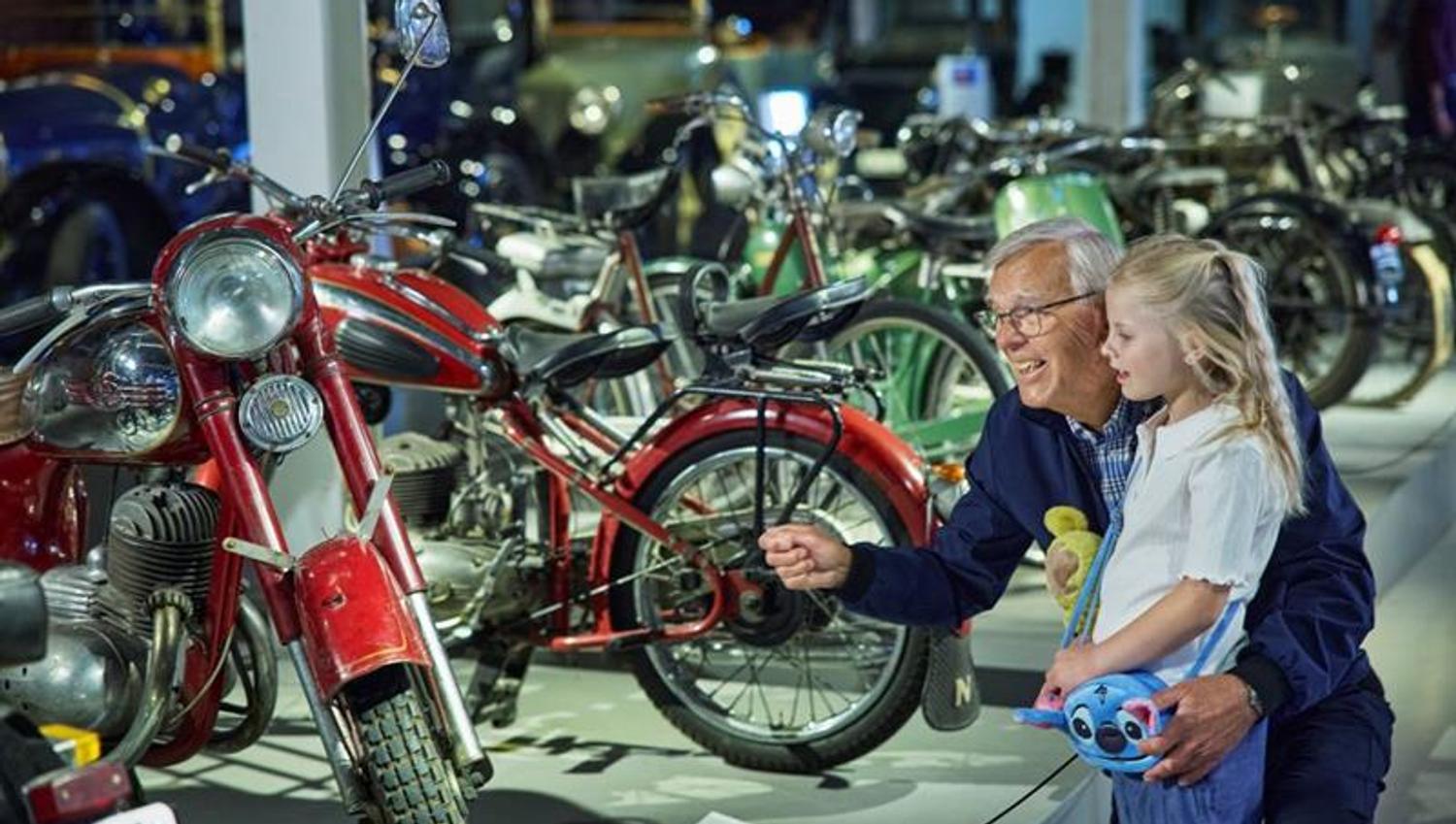 En eldre mann og en liten jente som ser på motorsykler