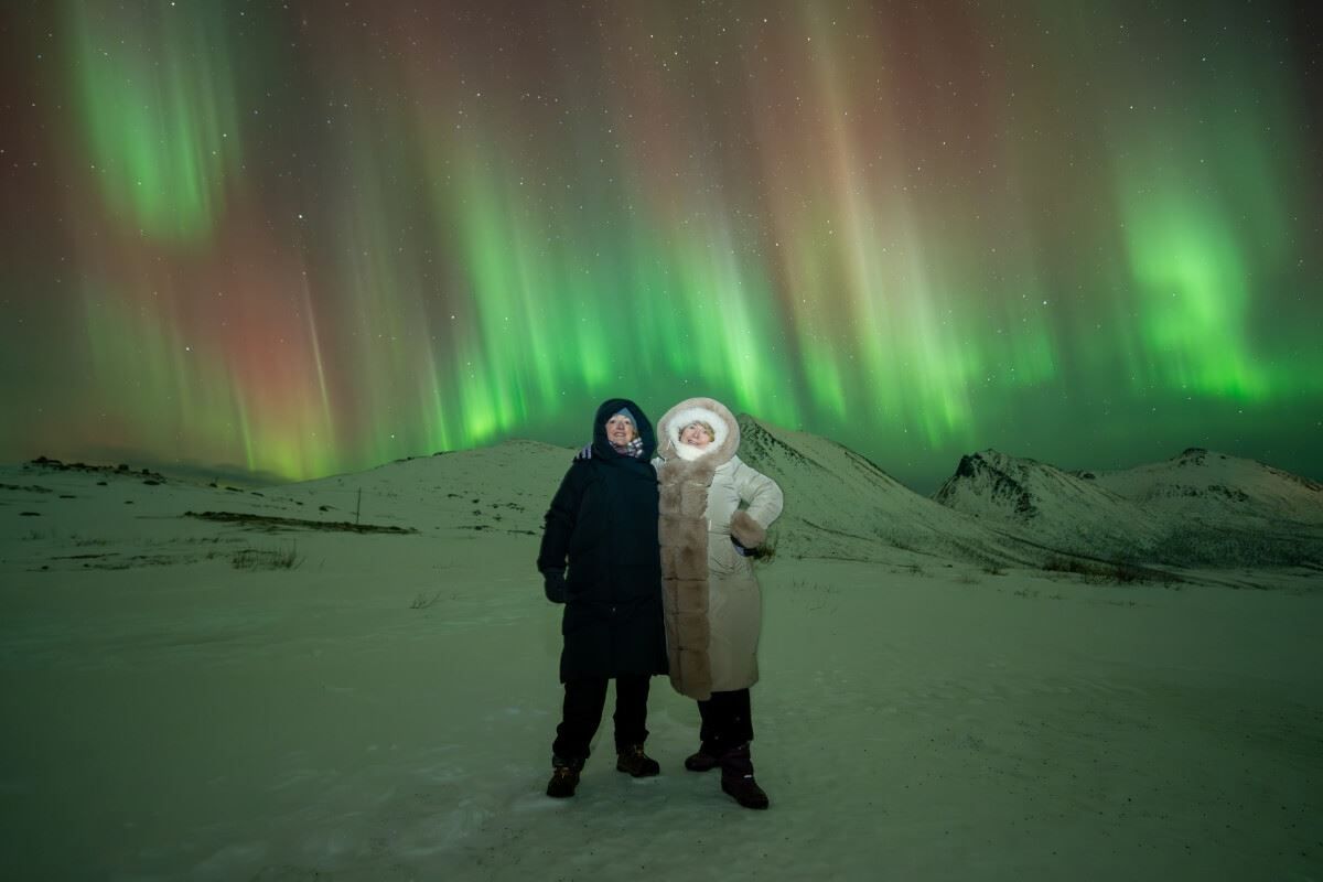 Strimler av nordlys danser bak et par