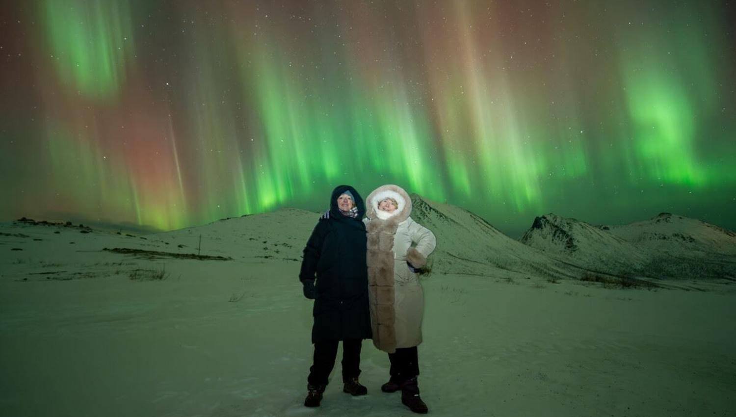 Strimler av nordlys danser bak et par