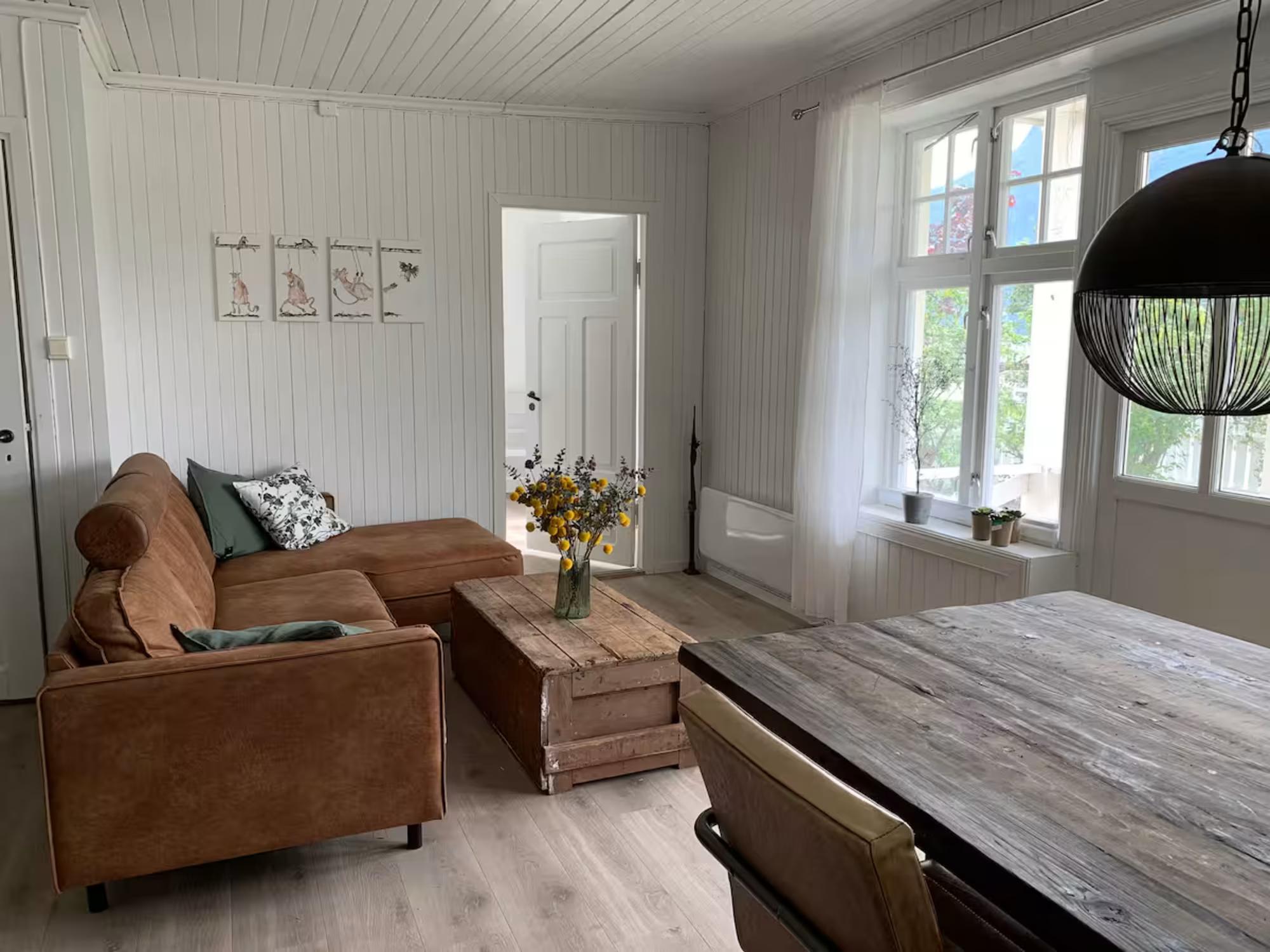 Koslig stue med sofagruppe og utsikt mot fjorden.