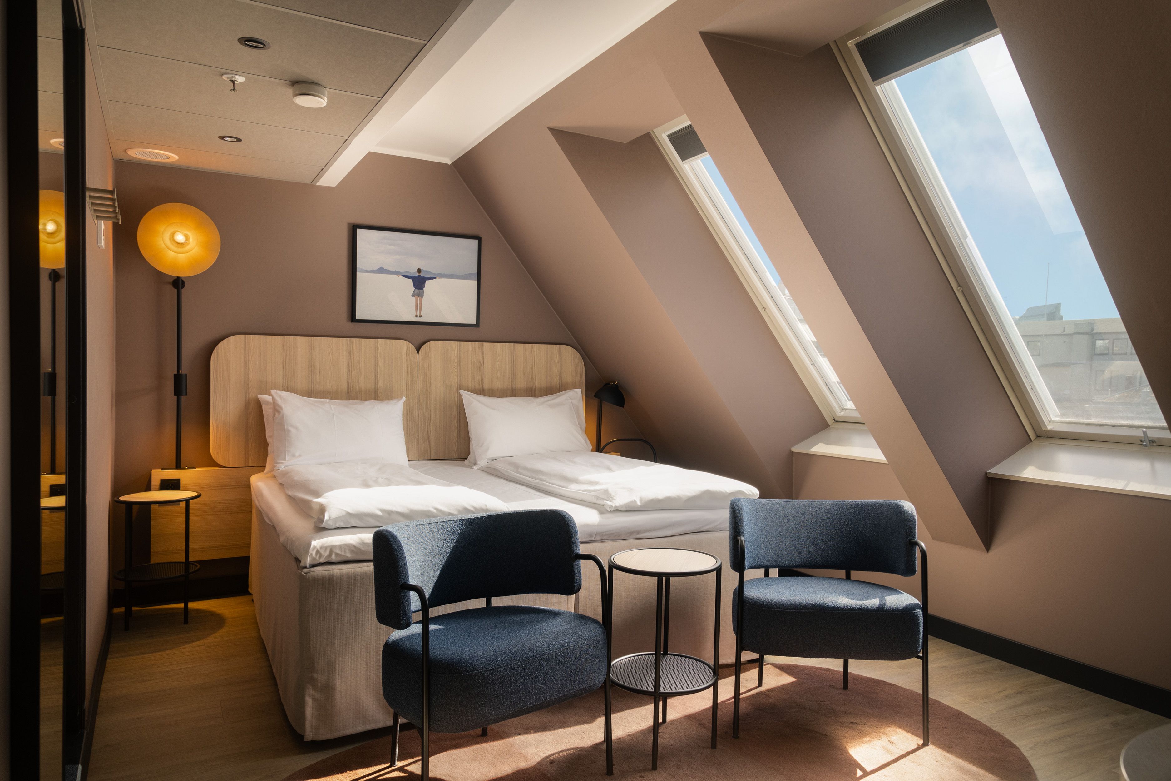 Hotel room with double bed, two armchairs and large windows