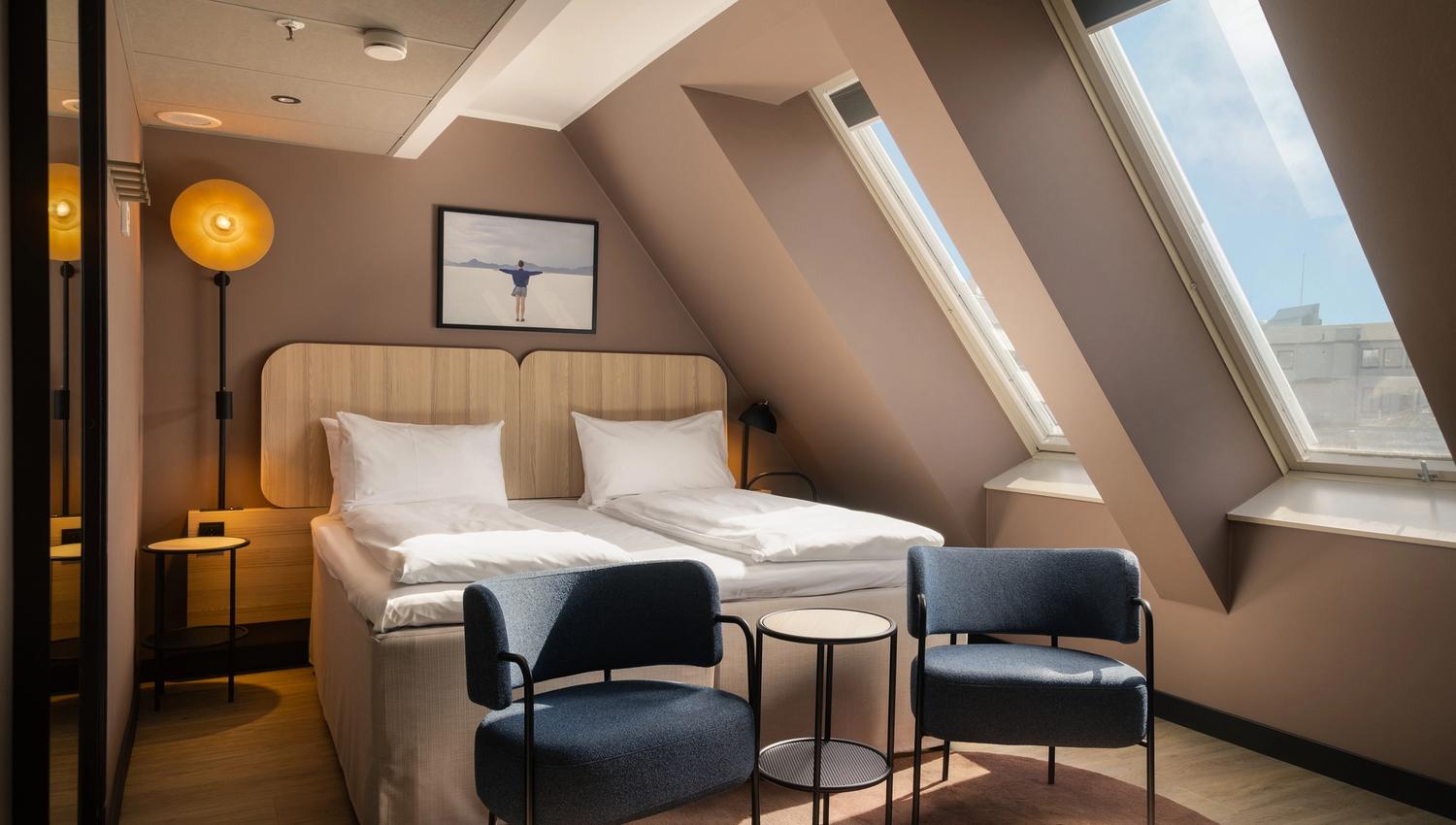 Hotel room with double bed, two armchairs and large windows