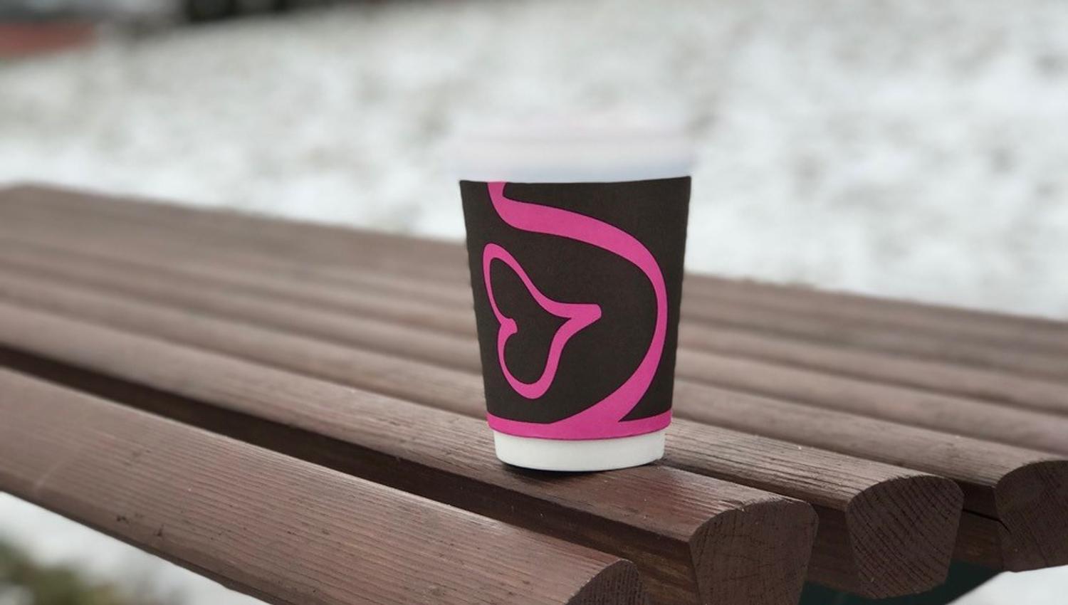 Pappkopp med kaffe ute på en benk på vinteren
