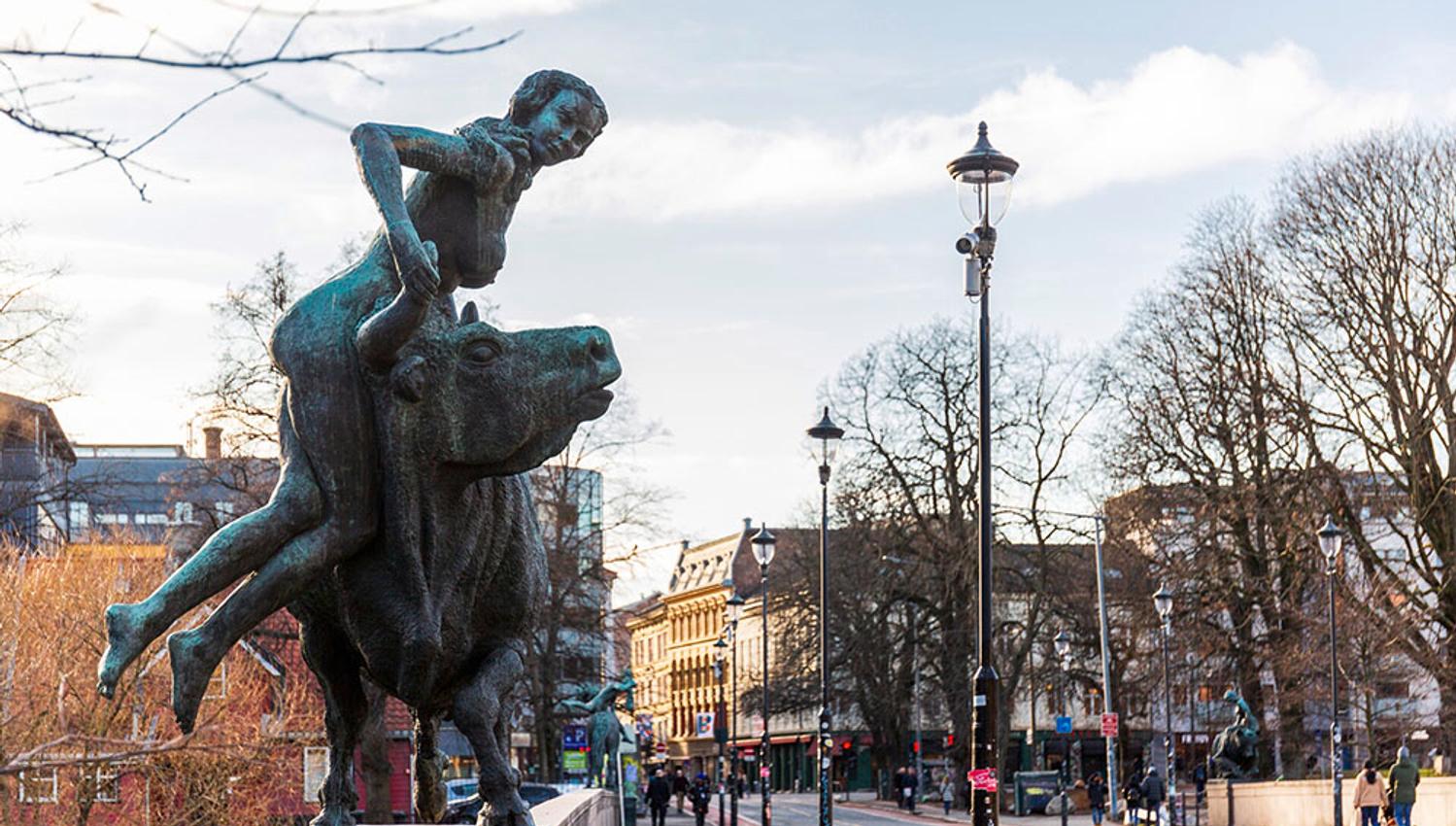 A statue of a girl hanging hanging from a bull on the bridge.
