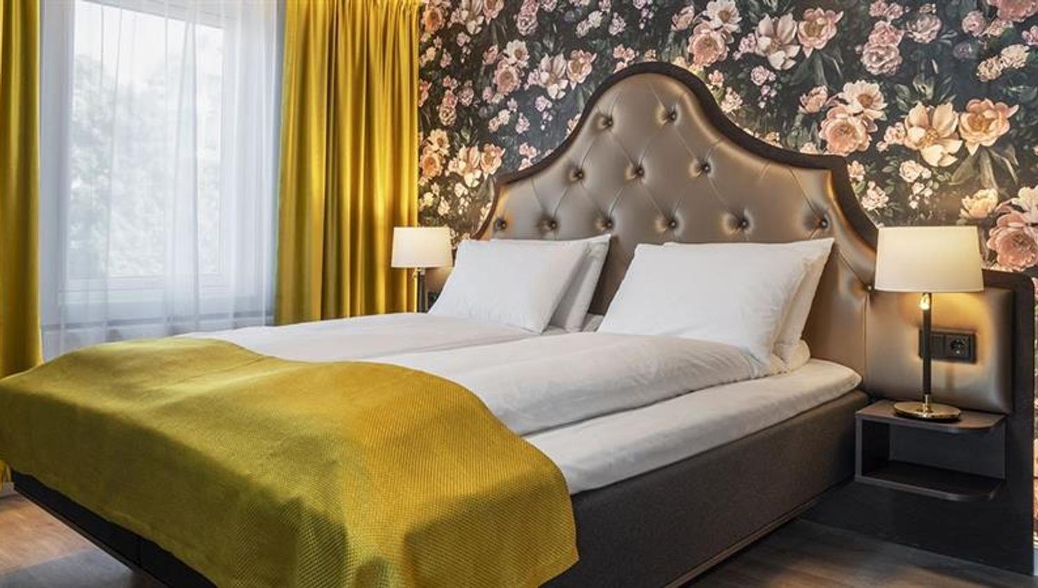 Soverom Thon Hotel Høyers. Seng med gult teppe, blomstrete tapet på vegg.