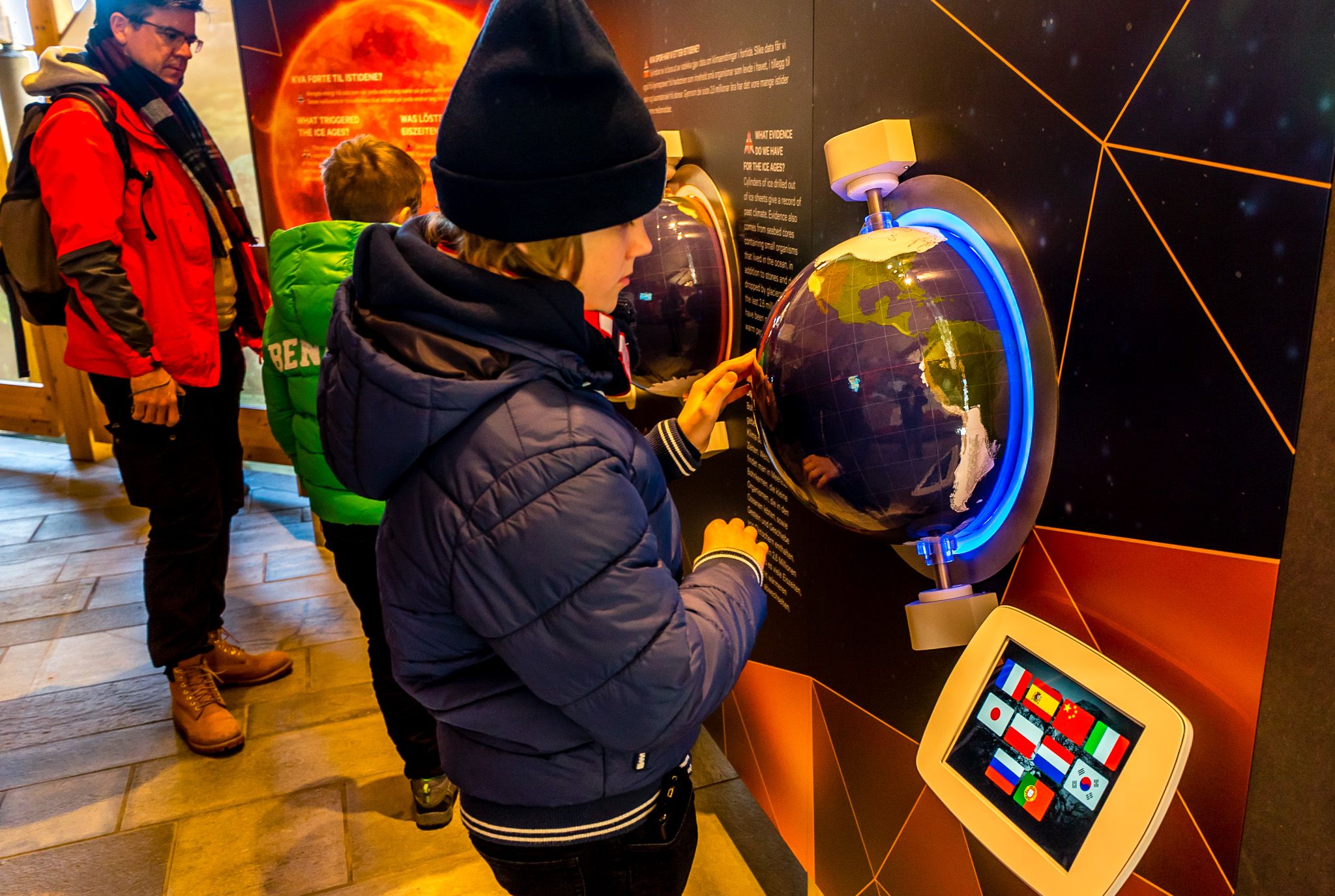 A boy playing with one of the interactive exhibition items, a globe in the wall.