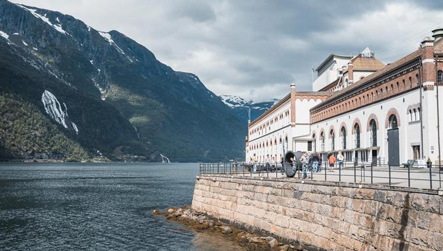 Bygningar frå Kraftmuseet i Hardanger med utsikt over fjorden, omgitt av vakre fjell og norsk natur.