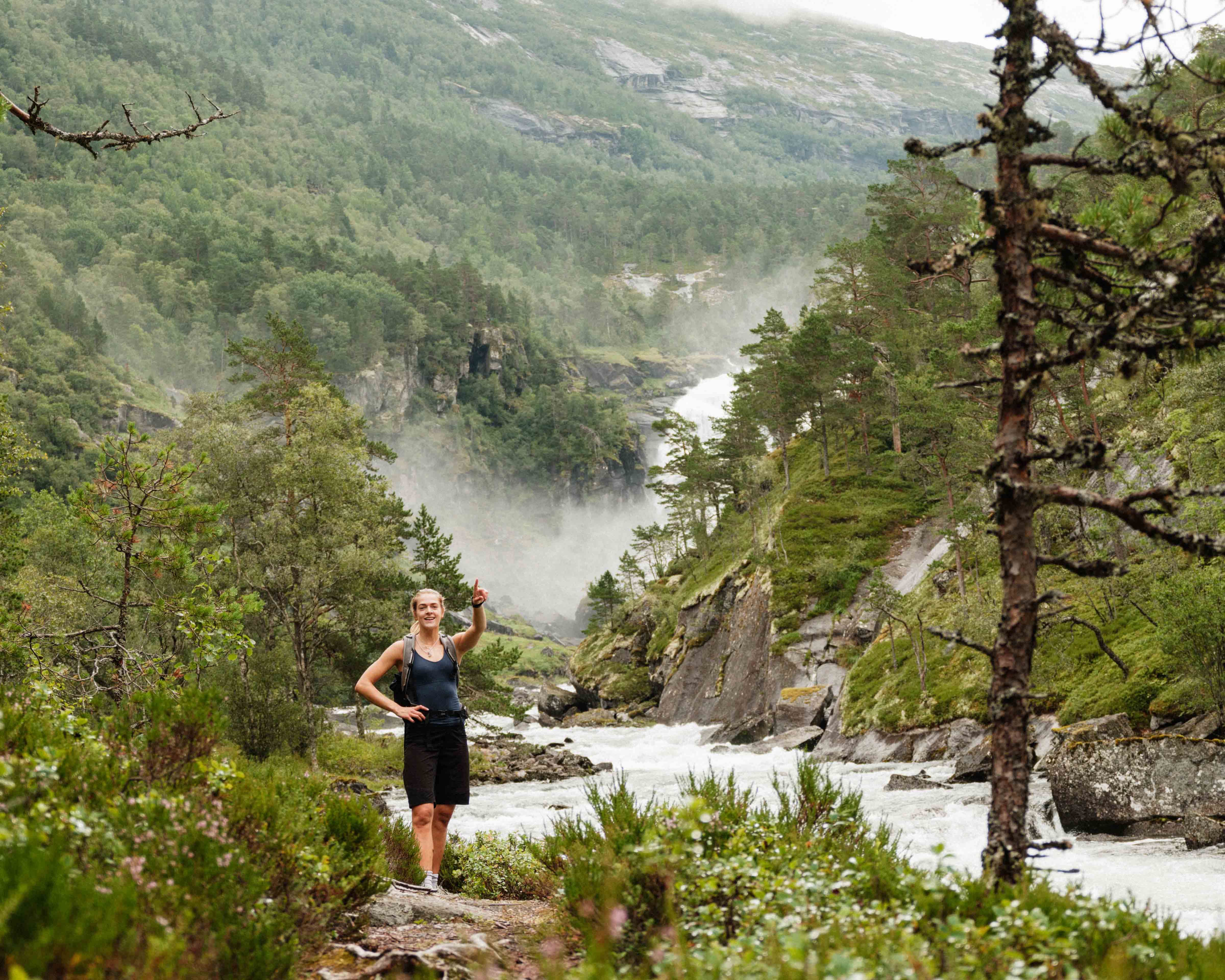 Turgåar peikar mot fossane i det fjerne – Husedalen byr på spektakulære naturopplevingar.