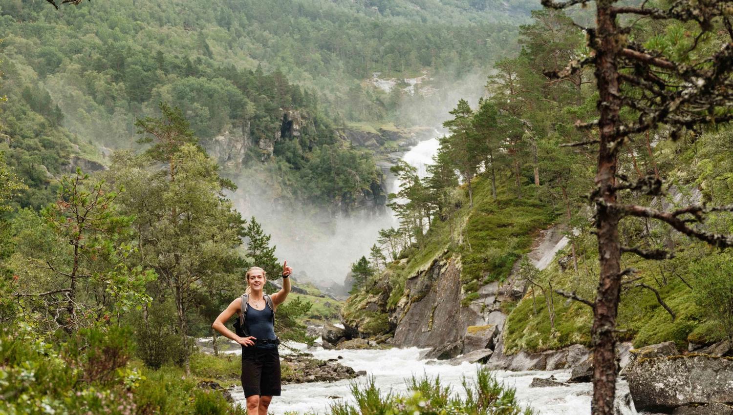 Turgåar peikar mot fossane i det fjerne – Husedalen byr på spektakulære naturopplevingar.
