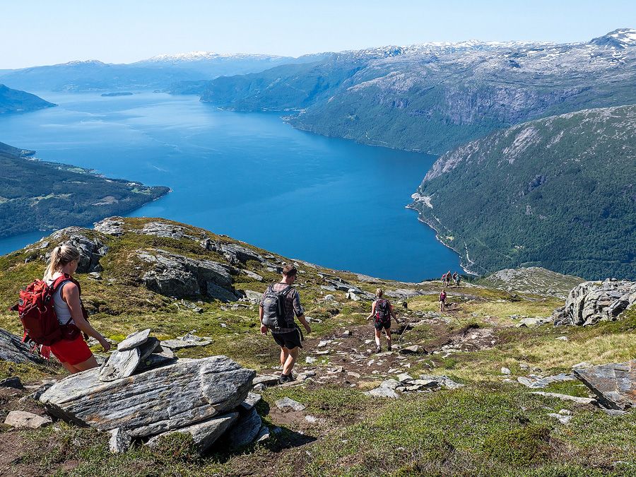 Gruppe turgåarar på veg nedover fjellet med blå fjordutsikt.