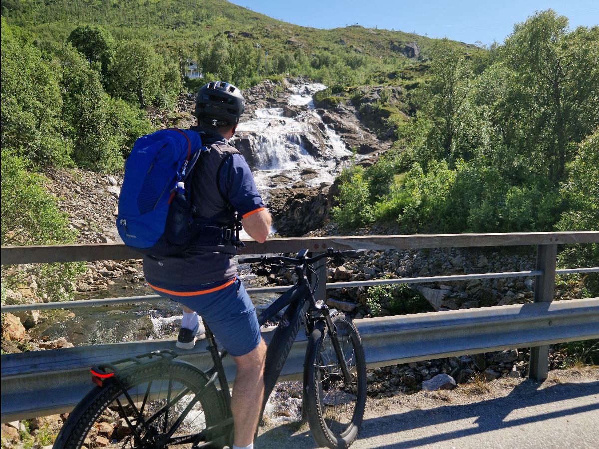 A person on a bike enjoying the view of a waterfall