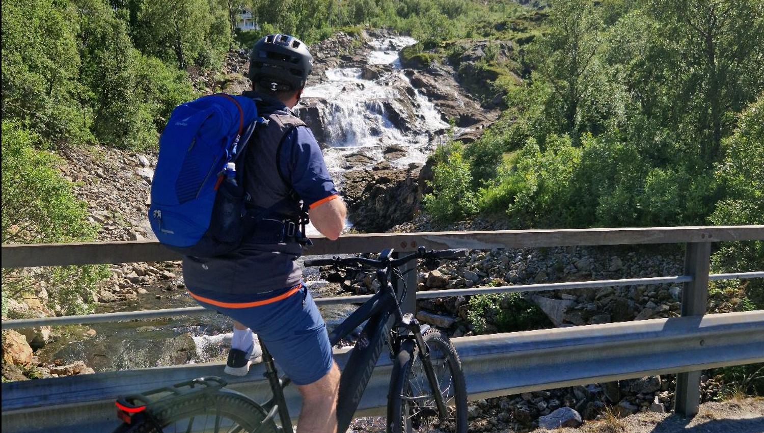 A person on a bike enjoying the view of a waterfall