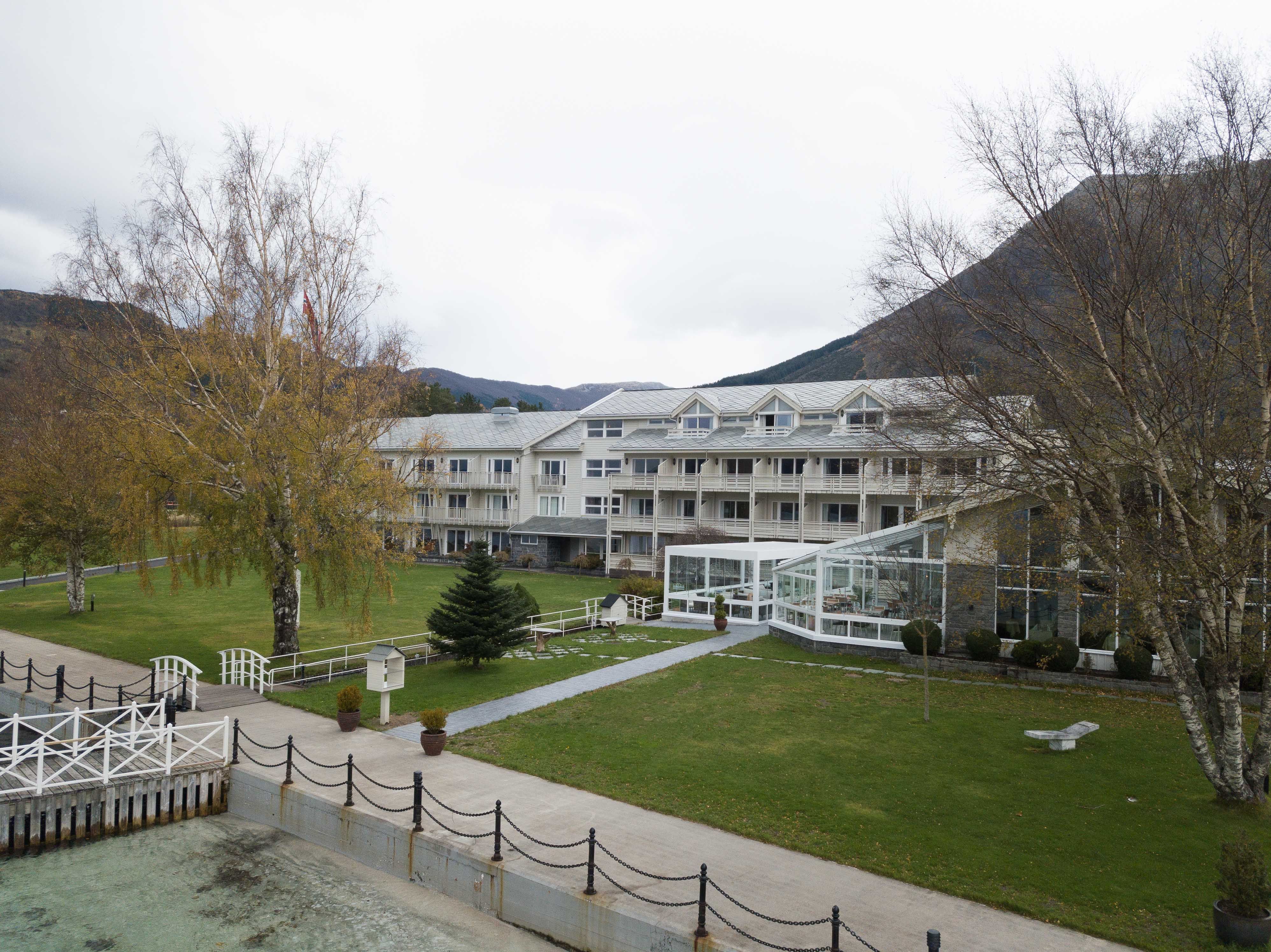 Rosendal Fjordhotel omgitt av grøne hagar og majestetiske fjell.