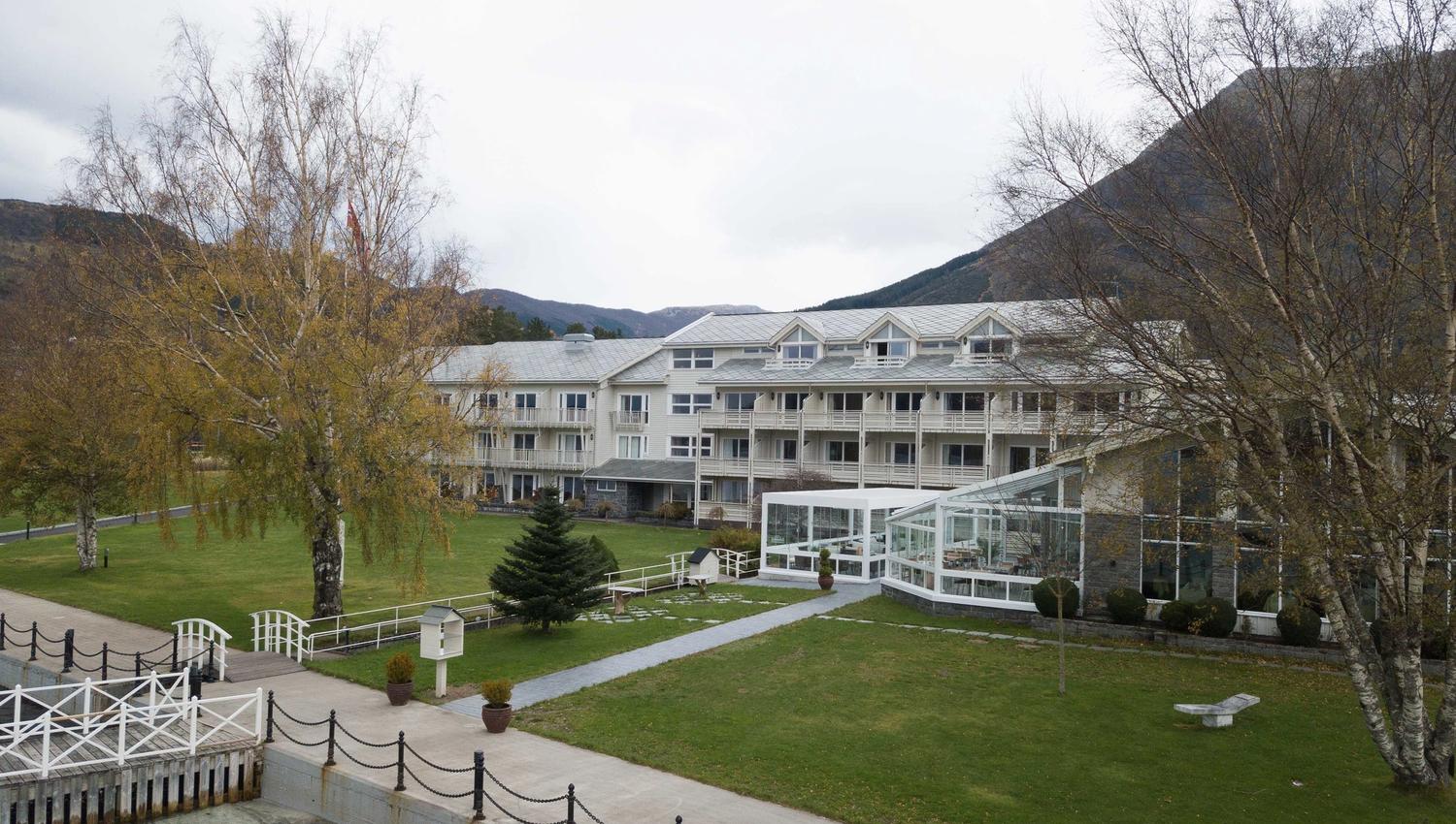 Rosendal Fjordhotel omgitt av grøne hagar og majestetiske fjell.