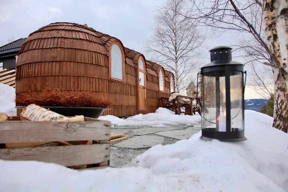 Wooden cabin pod and lantern on a snowy outdoor area.