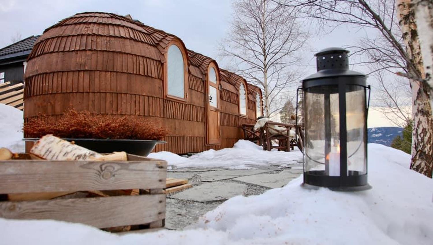 Wooden cabin pod and lantern on a snowy outdoor area.