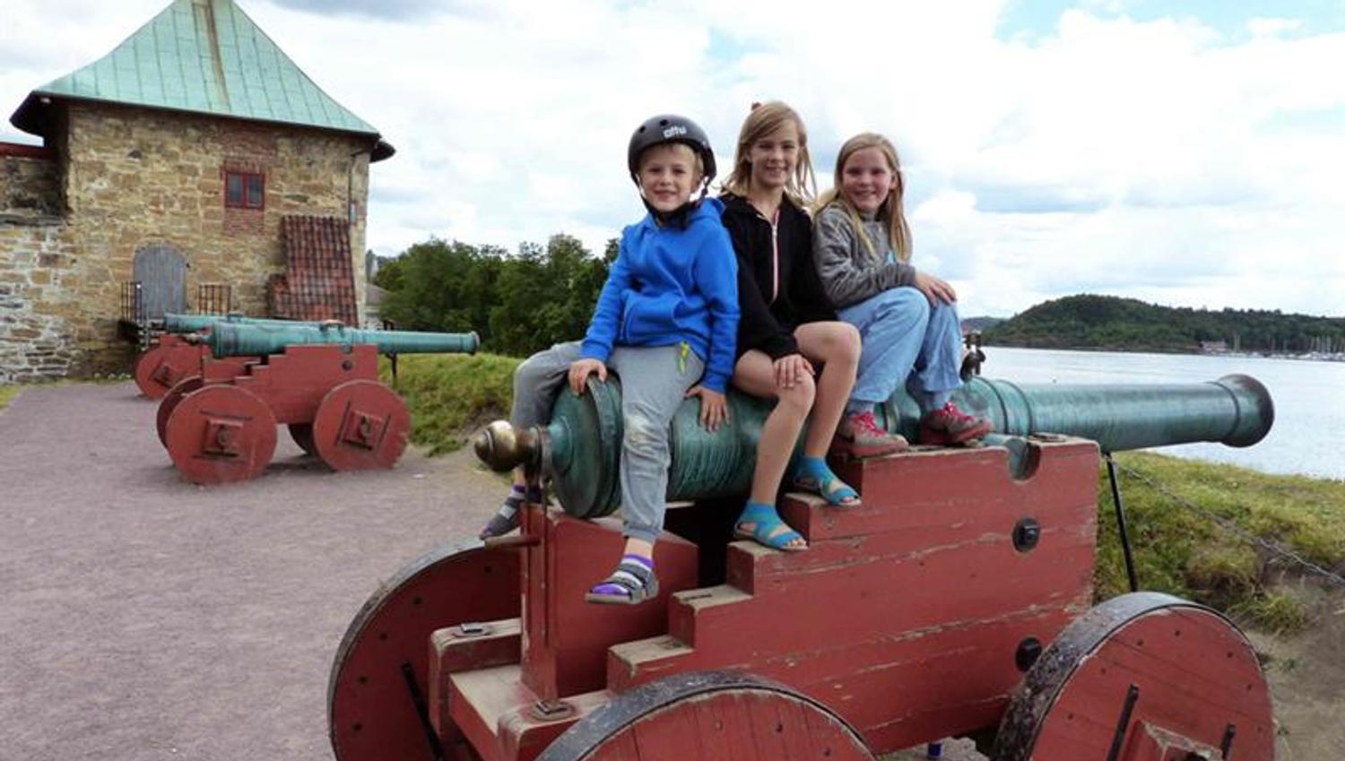 Tre barn som sitter på en kanon.